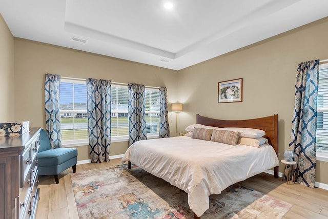 bedroom featuring light hardwood / wood-style flooring and a raised ceiling