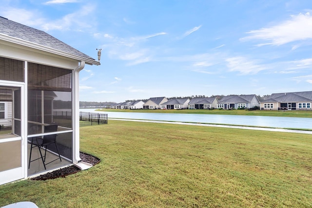 view of yard with a sunroom and a water view