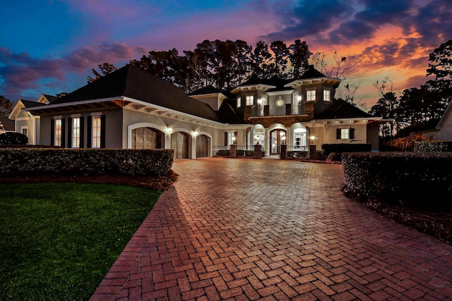 view of front of house featuring decorative driveway, an attached garage, and stucco siding