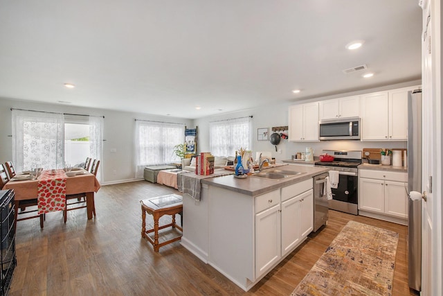 kitchen with appliances with stainless steel finishes, a sink, an island with sink, white cabinets, and recessed lighting