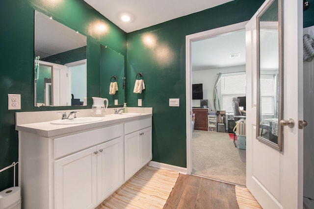 bathroom featuring wood finished floors, double vanity, and baseboards