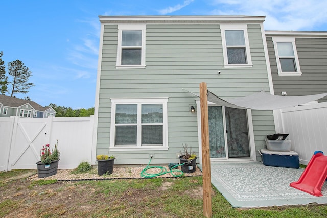 rear view of house featuring fence, a gate, and a patio
