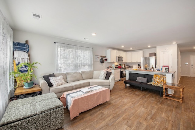 living area featuring light wood finished floors and recessed lighting