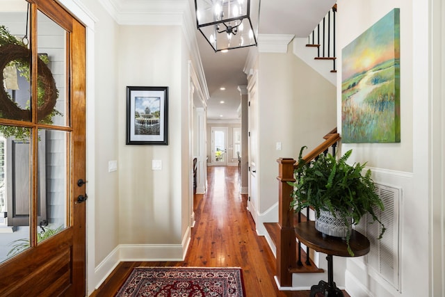 hall with a chandelier, dark hardwood / wood-style flooring, and ornamental molding