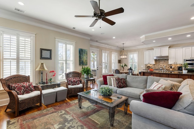 living room with a healthy amount of sunlight, dark hardwood / wood-style flooring, and ornamental molding