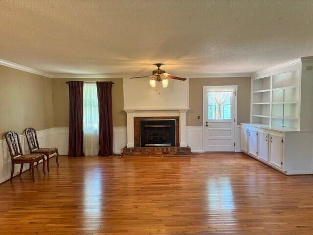 1153 Cherokee Dr, Manning, SC 29102 - unfurnished living room with a ceiling fan, a textured ceiling, light wood-style floors, ornamental molding, and a fireplace with raised hearth