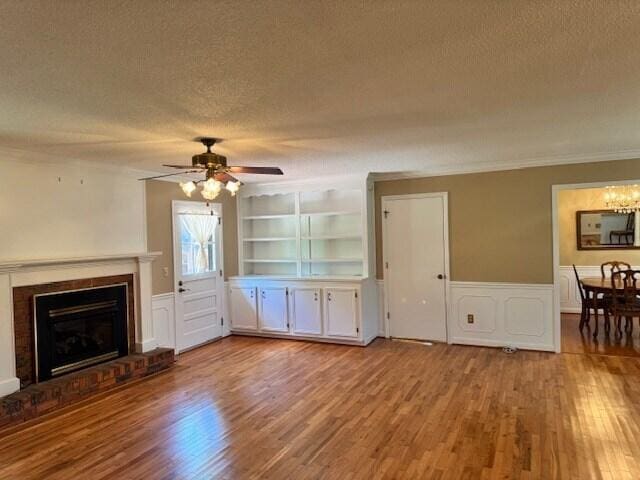 1153 Cherokee Dr, Manning, SC 29102 - unfurnished living room featuring a textured ceiling, wood finished floors, a wainscoted wall, a ceiling fan, and built in features