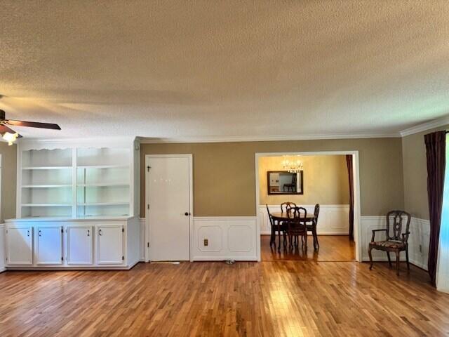 1153 Cherokee Dr, Manning, SC 29102 - dining area with a textured ceiling, wood finished floors, ceiling fan, a wainscoted wall, and crown molding