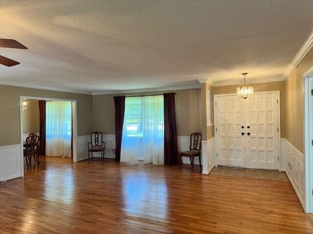 1153 Cherokee Dr, Manning, SC 29102 - entrance foyer featuring a textured ceiling, a wainscoted wall, crown molding, wood finished floors, and a chandelier
