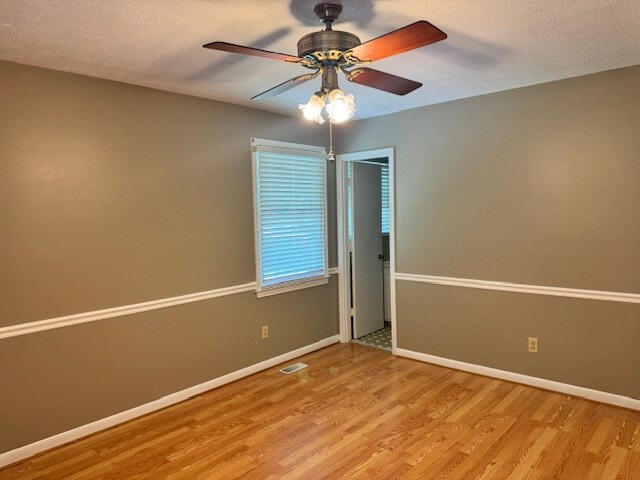 1153 Cherokee Dr, Manning, SC 29102 - unfurnished room featuring wood finished floors, baseboards, ceiling fan, and a textured ceiling