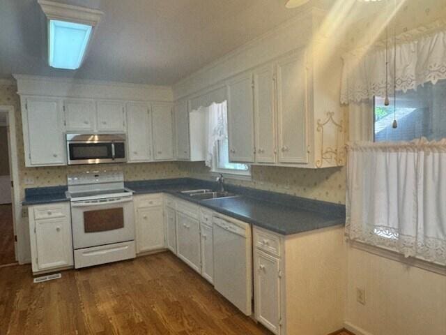 1153 Cherokee Dr, Manning, SC 29102 - kitchen featuring white appliances, a sink, plenty of natural light, dark countertops, and ornamental molding