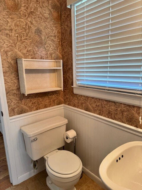 1153 Cherokee Dr, Manning, SC 29102 - bathroom with wallpapered walls, toilet, wainscoting, plenty of natural light, and tile patterned floors