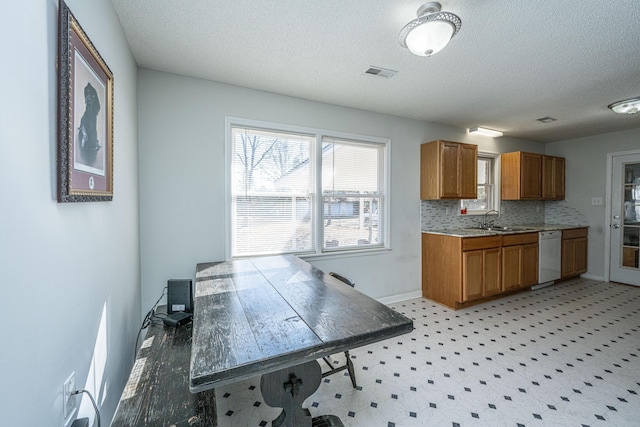 kitchen with sink, a textured ceiling, backsplash, and white dishwasher