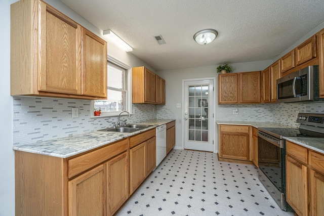 kitchen featuring stainless steel appliances, sink, decorative backsplash, and a textured ceiling