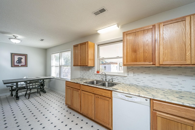 kitchen featuring sink, dishwasher, backsplash, light stone counters, and a textured ceiling