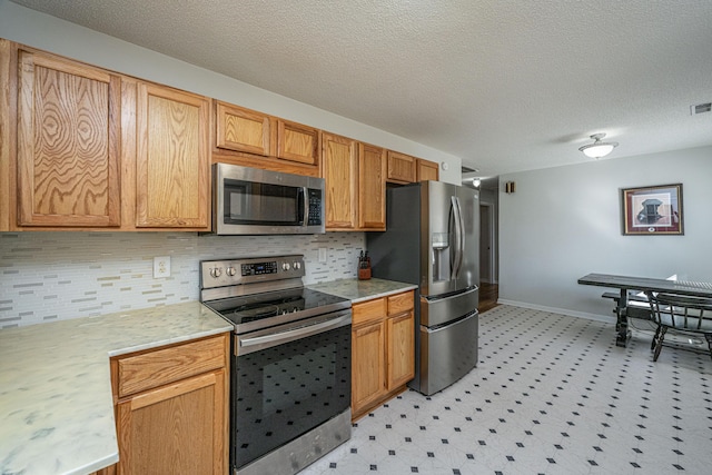 kitchen featuring stainless steel appliances, decorative backsplash, and a textured ceiling