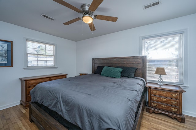 bedroom with multiple windows, light hardwood / wood-style floors, and ceiling fan