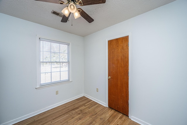 spare room with ceiling fan, light hardwood / wood-style floors, and a textured ceiling