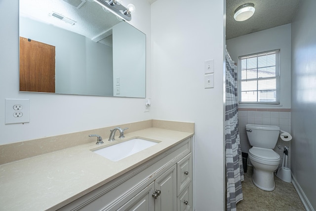 bathroom featuring vanity, a textured ceiling, toilet, and tile walls