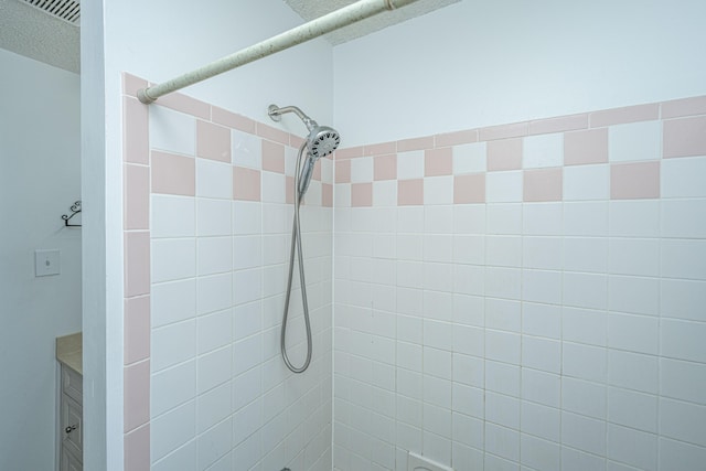 bathroom featuring a tile shower and a textured ceiling