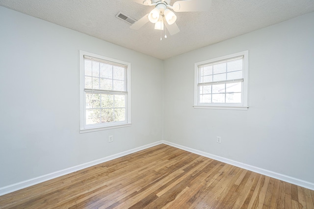 unfurnished room featuring ceiling fan, hardwood / wood-style floors, a textured ceiling, and a wealth of natural light