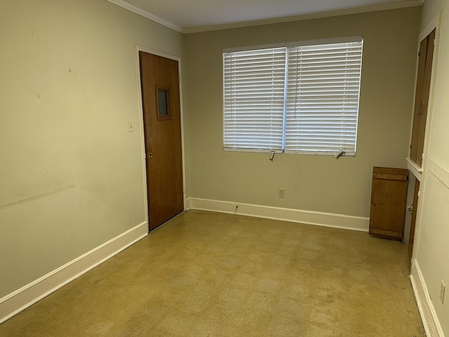 empty room featuring crown molding and baseboards