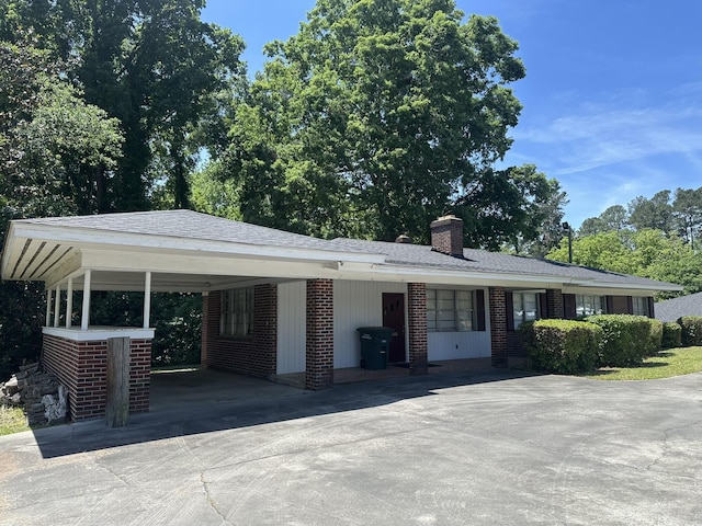 view of front of property with brick siding, driveway, and a chimney