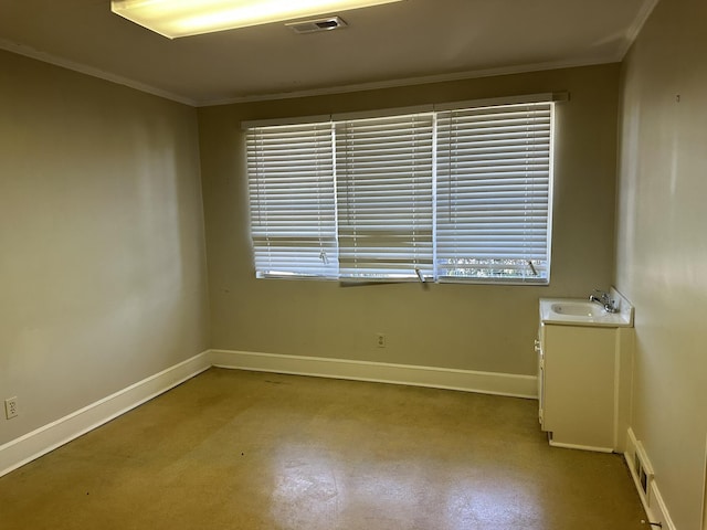 spare room with baseboards, ornamental molding, a healthy amount of sunlight, visible vents, and a sink