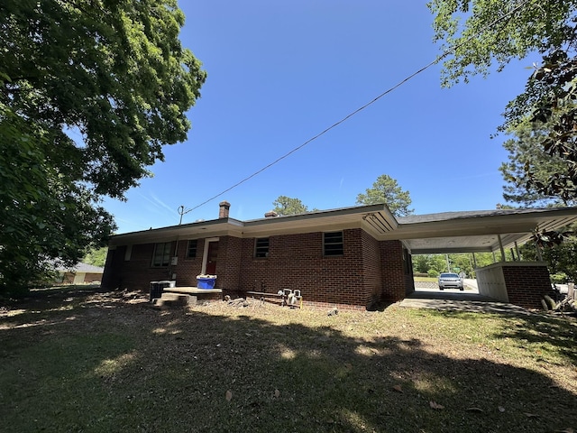 back of property with brick siding and a carport