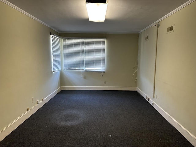 empty room with baseboards, ornamental molding, dark colored carpet, and visible vents