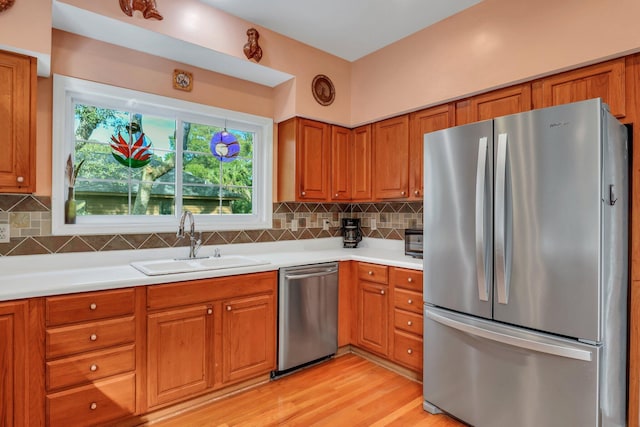 kitchen featuring decorative backsplash, appliances with stainless steel finishes, light hardwood / wood-style flooring, and sink