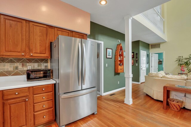 kitchen with decorative backsplash, stainless steel fridge, and light hardwood / wood-style floors