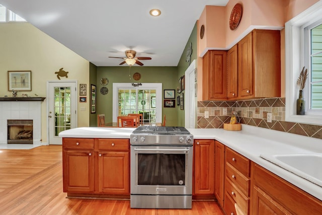 kitchen featuring stainless steel range, light wood-type flooring, and a tile fireplace