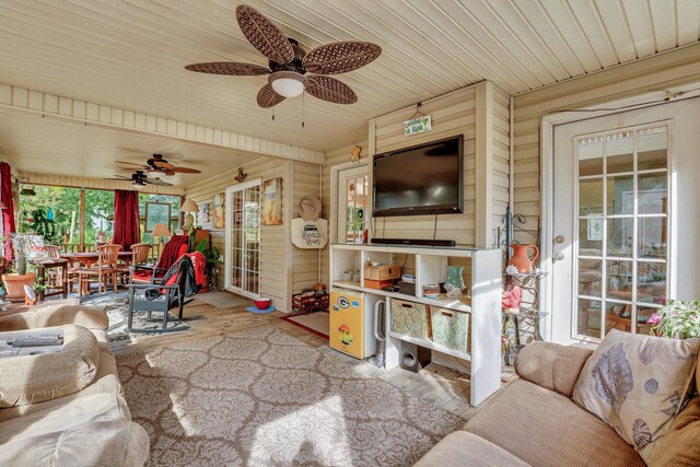 living room with wood ceiling, ceiling fan, light wood-type flooring, and wooden walls