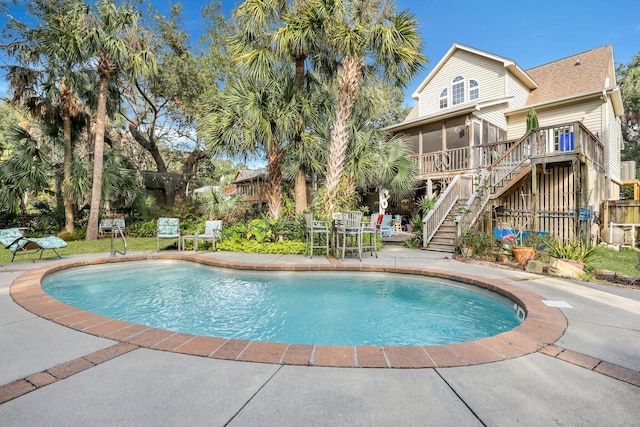 view of pool with a sunroom and a patio