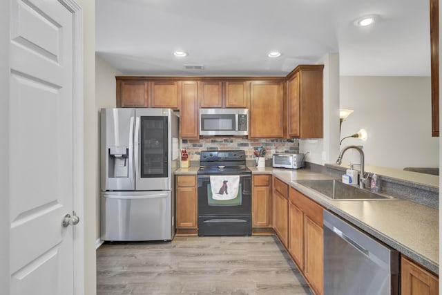 1005 Washitonia Way Unit B, Charleston, SC 29492 - kitchen with appliances with stainless steel finishes, a sink, brown cabinetry, decorative backsplash, and light wood-type flooring