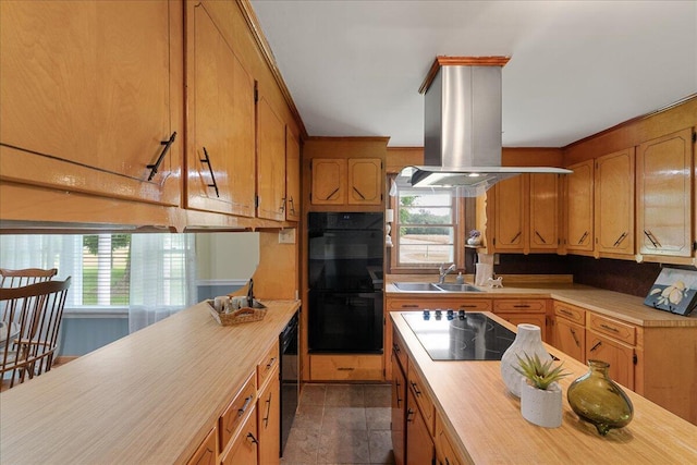 kitchen with dark tile patterned flooring, black appliances, island exhaust hood, and sink