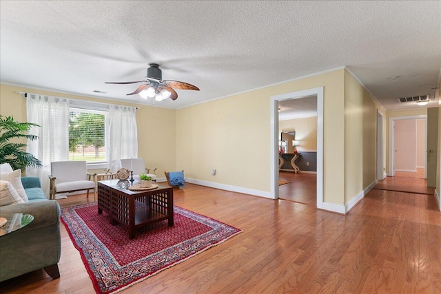 living room featuring wood-type flooring, a textured ceiling, crown molding, and ceiling fan