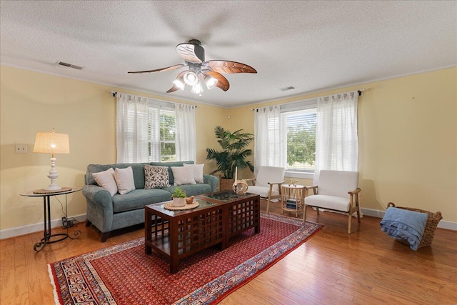 living room featuring a wealth of natural light, ceiling fan, hardwood / wood-style flooring, and a textured ceiling