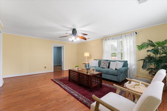 living room with wood-type flooring, crown molding, and ceiling fan