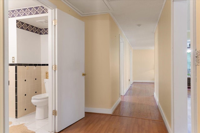 corridor with tile walls and light hardwood / wood-style floors