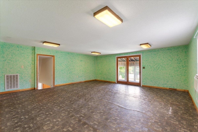 unfurnished room featuring french doors, a textured ceiling, and dark parquet flooring