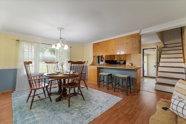 dining area with crown molding, an inviting chandelier, and hardwood / wood-style floors