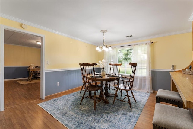 dining space featuring crown molding, a chandelier, hardwood / wood-style floors, and wood walls