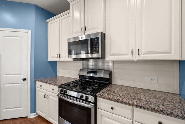 kitchen with dark stone countertops, white cabinetry, and appliances with stainless steel finishes