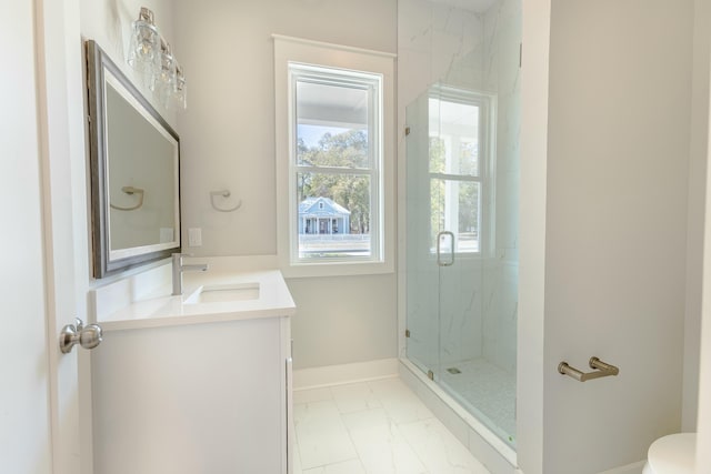 bathroom with toilet, vanity, baseboards, marble finish floor, and a marble finish shower