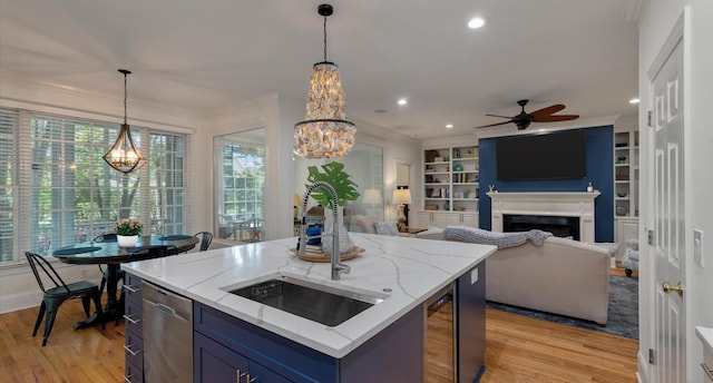 kitchen with light wood-type flooring, blue cabinetry, dishwasher, ceiling fan with notable chandelier, and a sink