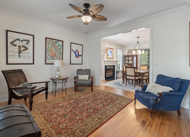 living area with a ceiling fan, crown molding, and wood finished floors