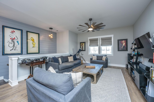 living room with ceiling fan, wooden walls, and light hardwood / wood-style floors