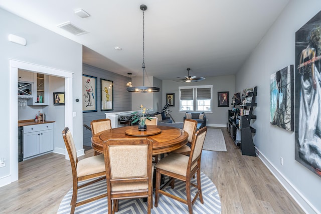 dining space featuring ceiling fan with notable chandelier and light wood-type flooring